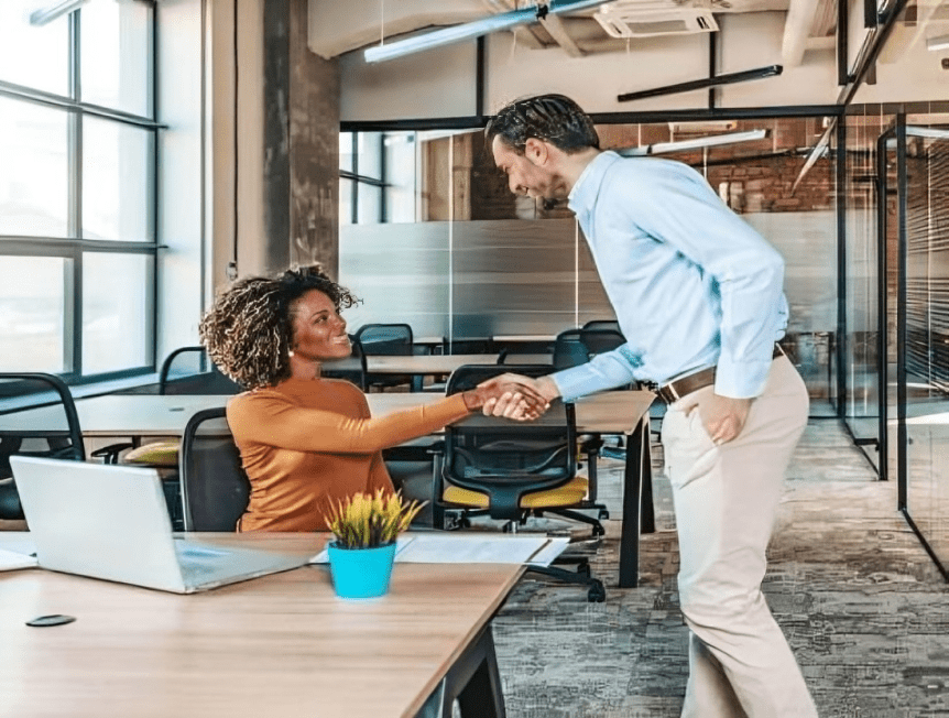 Two people shaking hands in an office setting.