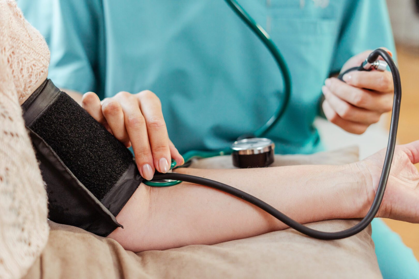 Female doctor measuring blood pressure of senior woman at home selective focus on hand, closeup. Treatment, health care concept